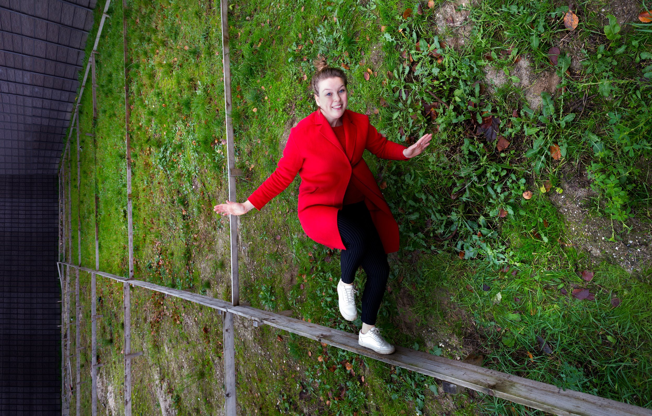 Vrouw met rode jas in groene tuin